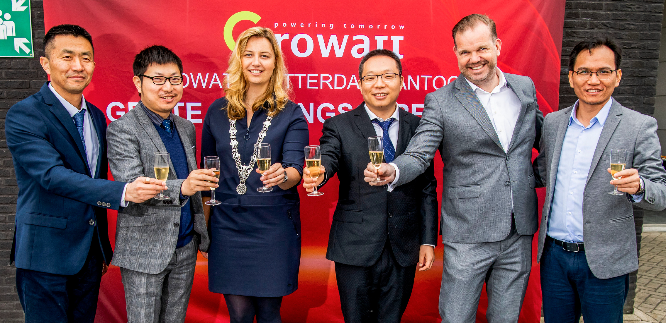 David Ding, Growatt Niderland ofisi, Ramon Li, Growatt-ın Avropa direktoru, qırmızı banner önündə şampan stəkanları tutan rəsmi geyimli insanlar qrupu.